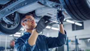 Portrait Shot of a Handsome Mechanic Working on a Vehicle in a C